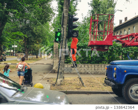 Worker of electric service company repair traffic lights in the city. Installation of a traffic light in the city. Worker of electric service company repair traffic lights in the city. Installation of a traffic light in the city. 138642364