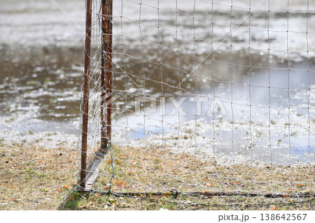 閉校となった小学校の荒れた校庭。雨上がりのグランドの水たまりと残されたサッカーゴール。冬の風景。 138642567