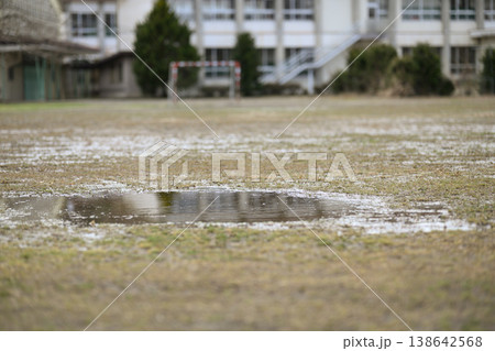 閉校となった小学校の荒れた校庭。雨上がりのグランドの水たまりと残されたサッカーゴール。冬の風景。 138642568