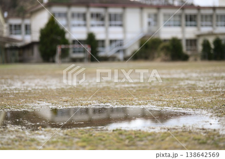 閉校となった小学校の荒れた校庭。雨上がりのグランドの水たまりと残されたサッカーゴール。冬の風景。 138642569