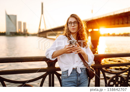 Young woman uses phone walk on embankment. Concept of vacation, technology, weekend. 138642707