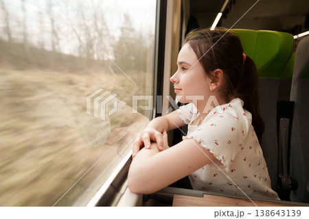 Girl looking through train window during journey Girl looking through train window during journey 138643139