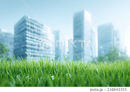 Green grass foreground in city park with buildings in the background. Harmony between lush fields and glass buildings blurred skyline. Sustainable urban renewal scene. Smart city futuristic cityscape 138643355