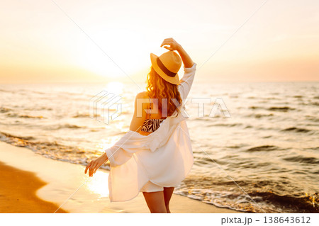 Carefree woman tourist walking along ocean sandy beach at sunset. Travel, weekend, lifestyle concept Carefree woman tourist walking along ocean sandy beach at sunset. Travel, weekend, lifestyle concept 138643612