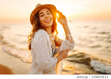 Carefree woman tourist walking along ocean sandy beach at sunset. Travel, weekend, lifestyle concept Carefree woman tourist walking along ocean sandy beach at sunset. Travel, weekend, lifestyle concept 138643613