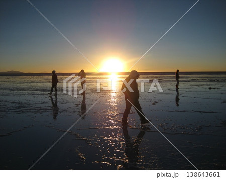ウユニ塩湖に沈む夕日とそぞろ歩く人々 138643661