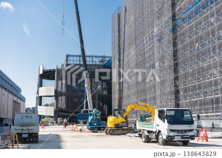 大規模鉄骨建設現場でクレーンと重機が稼働する新築工事の様子 足場に覆われた建物1 138643829