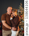 Couple poses together by the Christmas tree in a cozy setting 138644106