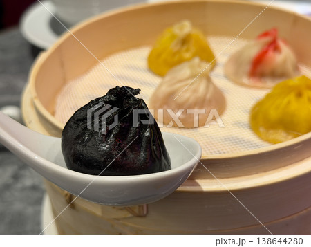 蒸篭料理。カラフルの味付き小籠包。黒色の小籠包のクローズアップ。 蒸篭料理。カラフルの味付き小籠包。黒色の小籠包のクローズアップ。 138644280