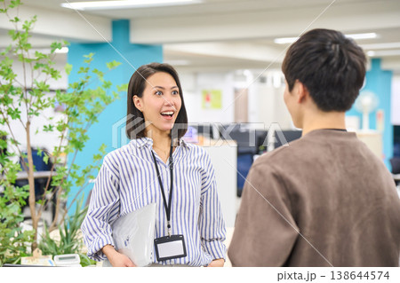 オフィスでデバイスを持ち同僚の男性と笑顔で話す女性社員 オフィスでデバイスを持ち同僚の男性と笑顔で話す女性社員 138644574