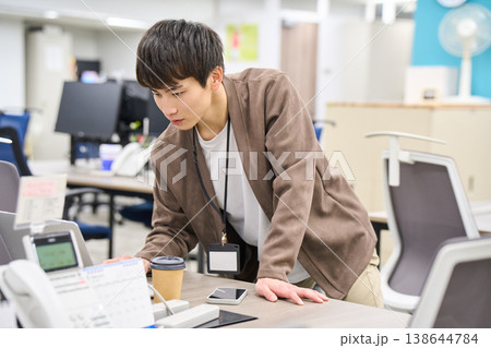 フリーアドレスのオフィスで立ったままノートパソコンの画面を確認する若い男性社員 フリーアドレスのオフィスで立ったままノートパソコンの画面を確認する若い男性社員 138644784