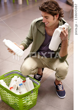 Man, milk and product comparison in grocery store, choice or shopping basket selection. Male person, smile and dairy drink for supermarket decision, expiry date information or reading nutrition value Man, milk and product comparison in grocery store, choice or shopping basket selection. Male person, smile and dairy drink for supermarket decision, expiry date information or reading nutrition value 138645087