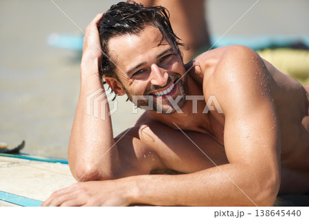 Beach, surfing and portrait of happy man relax, tired and rest after island activity, outdoor cardio or summer freedom. Australia holiday, sports and wet person smile, happiness or lying on surfboard 138645440
