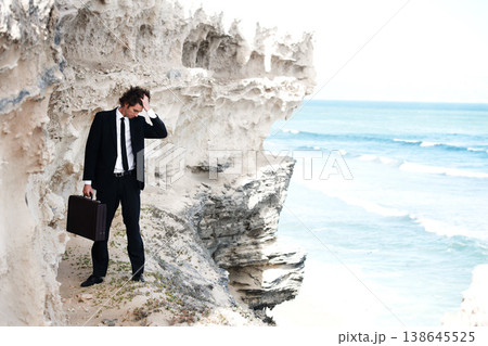 Business, briefcase and man with stress, cliff and depression with burnout, jobless and mental health. Person, employee and consultant with ocean, formal and fail with mistake, outdoor and suicide 138645525