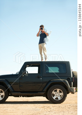 Photographer, man and camera on jeep outdoor for road trip, adventure or journey on rooftop with travel. Person, photography or memories for vacation, holiday or scenery in Asia or blue sky in nature 138645844