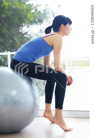Woman, sitting or exercise ball for rest with workout, training or pilates at home or studio with strength. Girl, wellness or healthy body with relaxing for fitness, performance and health at window 138646005