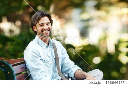 Nature, relax and portrait of a man on a park bench for a break, morning commute or travel. Smile, summer and a young person or tourist in a public garden for tourism, sightseeing or a vacation 138646135