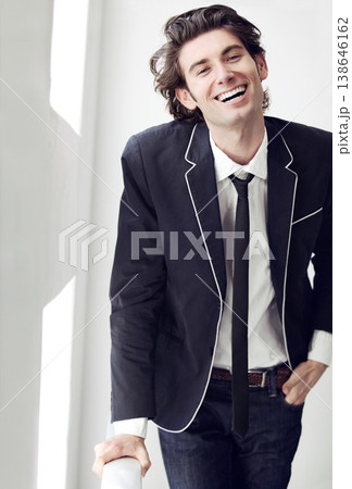 Happy, fashion and portrait of man by a wall with formal, stylish and classy outfit for confidence. Smile, suit and young male model with elegant, cool and trendy style by white background space. Happy, fashion and portrait of man by a wall with formal, stylish and classy outfit for confidence. Smile, suit and young male model with elegant, cool and trendy style by white background space. 138646162