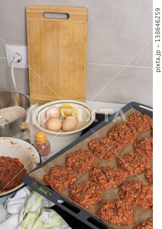 Liver cutlets are shaped and placed on a baking sheet. Ingredients like eggs, flour, and lemon sit on the counter Liver cutlets are shaped and placed on a baking sheet. Ingredients like eggs, flour, and lemon sit on the counter 138646259