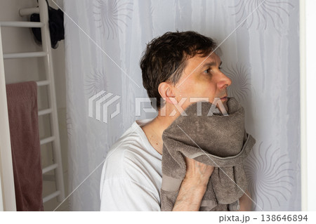 A 53-year-old man stands in a bathroom. He is drying his face with a towel after washing it. The man appears focused as he prepares for the day ahead A 53-year-old man stands in a bathroom. He is drying his face with a towel after washing it. The man appears focused as he prepares for the day ahead 138646894