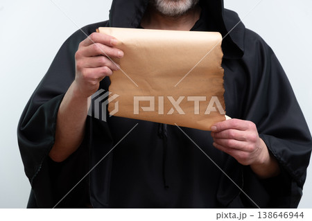 Monk in black robe reading old scroll, isolated. Monk in black robe reading old scroll, isolated. 138646944