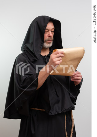 Monk in black robe reading scroll on white background, isolated. Monk in black robe reading scroll on white background, isolated. 138646946