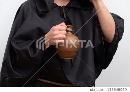 Hands of monk in black robe holding clay jug isolated on white background studio. 138646950