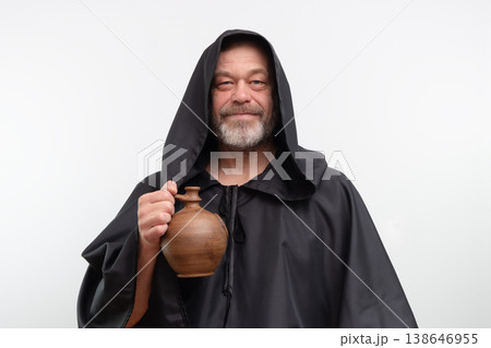 Male monk standing holding clay jug wearing black robe Male monk standing holding clay jug wearing black robe 138646955