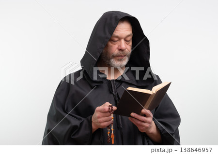 Bearded monk wearing hood holding book and rosary on white background. Bearded monk wearing hood holding book and rosary on white background. 138646957