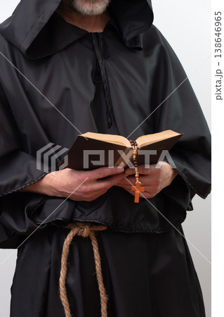 Bearded monk in hood focused reading text isolated. Bearded monk in hood focused reading text isolated. 138646965