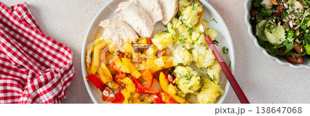 A wholesome dish featuring boiled potatoes, baked vegetables, chicken breast, and a vibrant salad with seeds 138647068