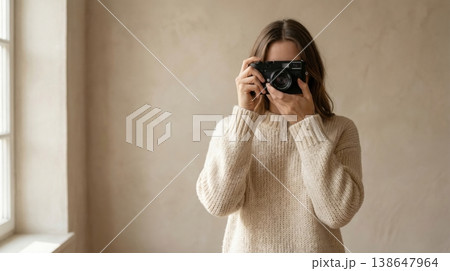 Minimalist Woman in Fluffy Sweater with Retro Camera on Beige 138647964