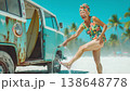 A woman stands near a vintage van at a tropical beach. She laughs as she splashes water on her feet. The sky is clear and the palm trees sway in the breeze. 138648778
