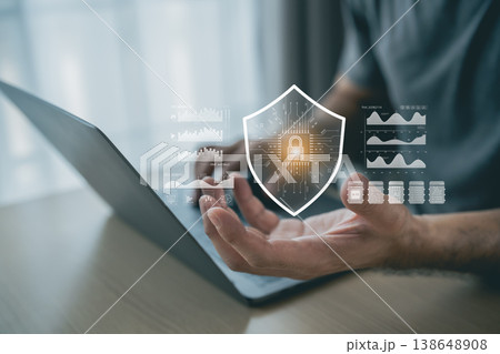 Hands of a person interacting with a laptop displaying digital security graphics and data analysis, representing cybersecurity concepts and technology innovations 138648908