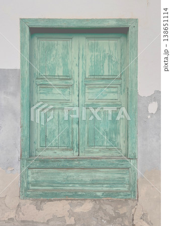 Weathered green wooden window shutters peeling paint 138651114