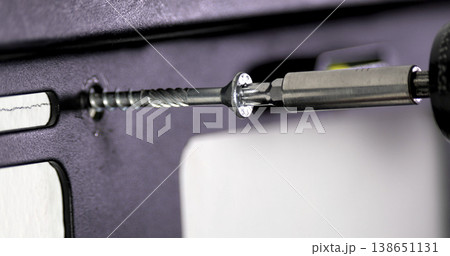 Screw being installed in a wall using a drill with a screwdriver bit in a home improvement project Screw being installed in a wall using a drill with a screwdriver bit in a home improvement project 138651131