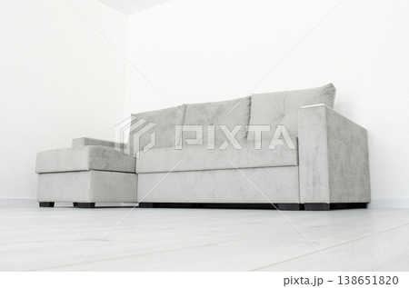 Grey sofa in a room with white wallpaper 138651820