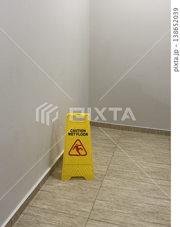 Caution wet floor sign on tiled floor in a brightly lit interior space with neutral colors Caution wet floor sign on tiled floor in a brightly lit interior space with neutral colors 138652039