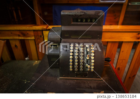 Classic black cash register elegantly displayed on a rustic wooden table in a cozy caf setting. Classic black cash register elegantly displayed on a rustic wooden table in a cozy caf setting. 138653184