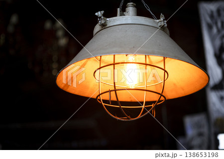 Vintage inspired industrial light fixture featuring a stylish bulb encased in a decorative metal cage design. 138653198
