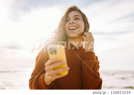 Young woman walks near lighthouse and chats with friends online. People, technology, leisure concept Young woman walks near lighthouse and chats with friends online. People, technology, leisure concept 138653234