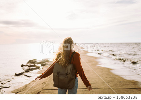 Woman enjoying breezy day near vibrant red lighthouse at sunset. Travel, weekend, lifestyle concept. Woman enjoying breezy day near vibrant red lighthouse at sunset. Travel, weekend, lifestyle concept. 138653238