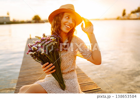 Young woman in dress sitting on wooden pier near pond. Rustic style of wedding. Travel, tourism Young woman in dress sitting on wooden pier near pond. Rustic style of wedding. Travel, tourism 138653584