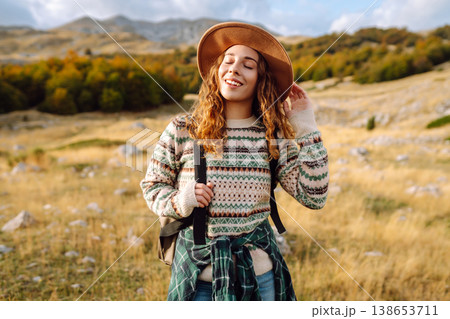 Young woman enjoys sunny afternoon in mountains while sitting on rocks. Tourism. Active lifestyle. Young woman enjoys sunny afternoon in mountains while sitting on rocks. Tourism. Active lifestyle. 138653711