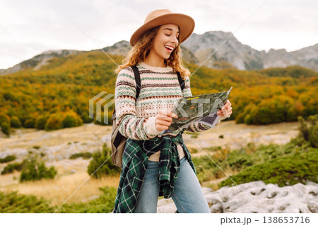 Young woman hiking in autumn landscape with a map. Travel, nature concept. Active lifestyle. Young woman hiking in autumn landscape with a map. Travel, nature concept. Active lifestyle. 138653716