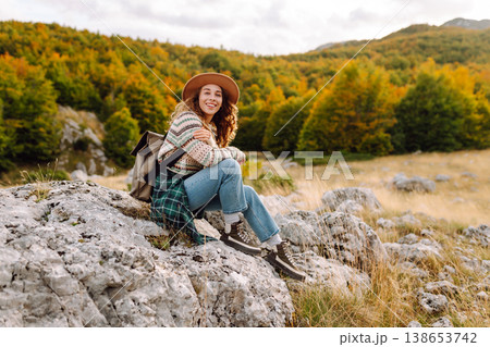 Young woman enjoys sunny afternoon in mountains while sitting on rocks. Tourism. Active lifestyle. Young woman enjoys sunny afternoon in mountains while sitting on rocks. Tourism. Active lifestyle. 138653742