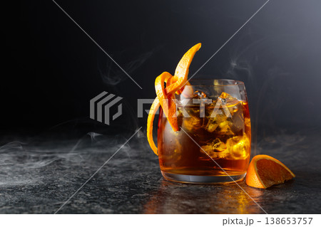 Whiskey with ice in a fogged up glass on a black stone table. Whiskey with ice in a fogged up glass on a black stone table. 138653757