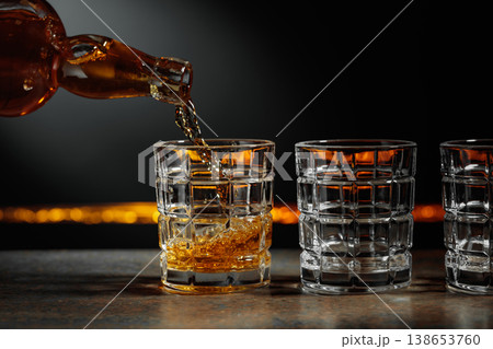 Whiskey is poured into a crystal glass. Whiskey is poured into a crystal glass. 138653760