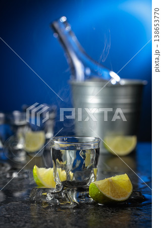 Vodka with lime slices on a black stone table. 138653770