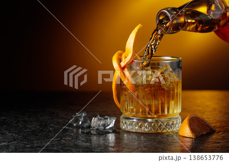 Old-fashioned cocktail in a fogged up glass on a black stone table. Old-fashioned cocktail in a fogged up glass on a black stone table. 138653776